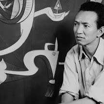 Black and white photograph of a cleanly shaven man sitting in front of an artwork comprised of abstract lines and shapes. He stares intently towards the left offscreen.