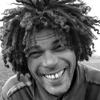 Black and white photograph of a man smiling broadly at the camera. 