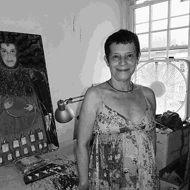 Black & white photograph of a smiling woman standing in front of a painting.