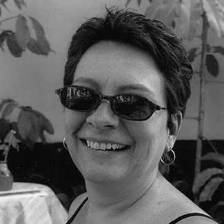 Black and white photograph of a woman wearing sunglasses smiling at the camera. 