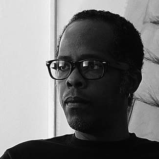 Black and white photograph of a man wearing glasses looking off to the left. 